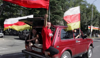 People wave a South Ossetian and a Russian flag